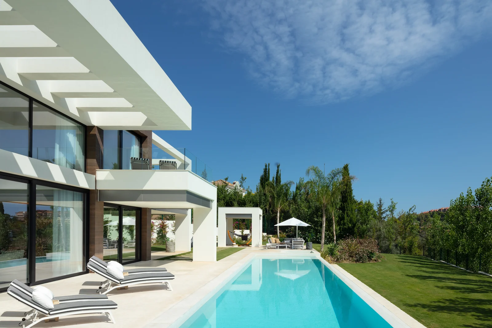 Villa contemporánea con piscina alargada, tumbonas y jardín
