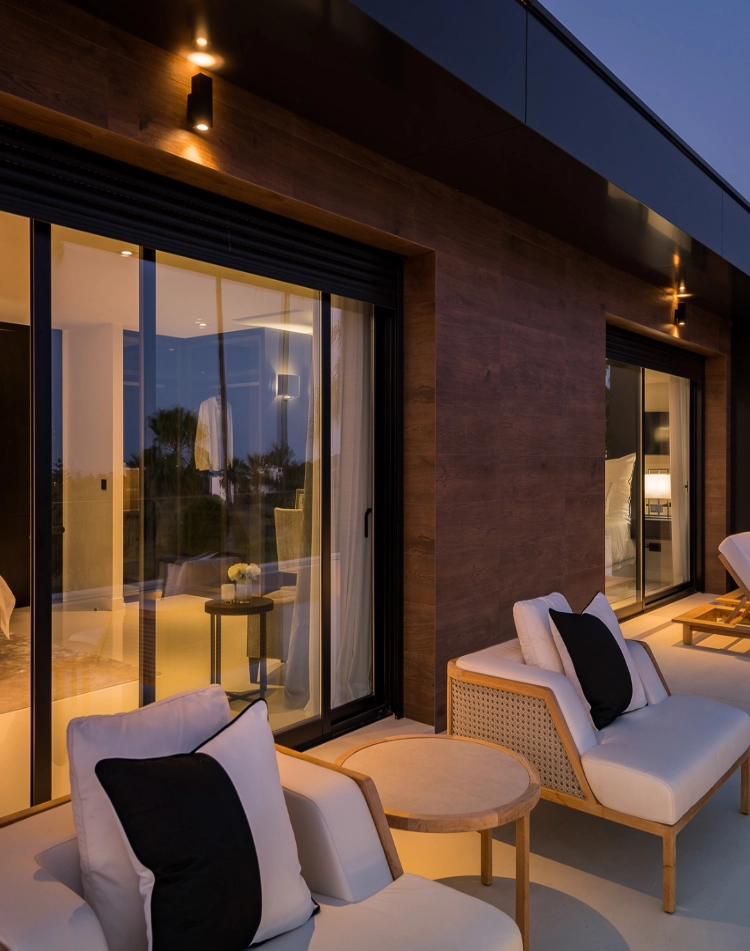 Terraza cubierta con sofás exteriores e iluminación cálida en una vivienda de lujo