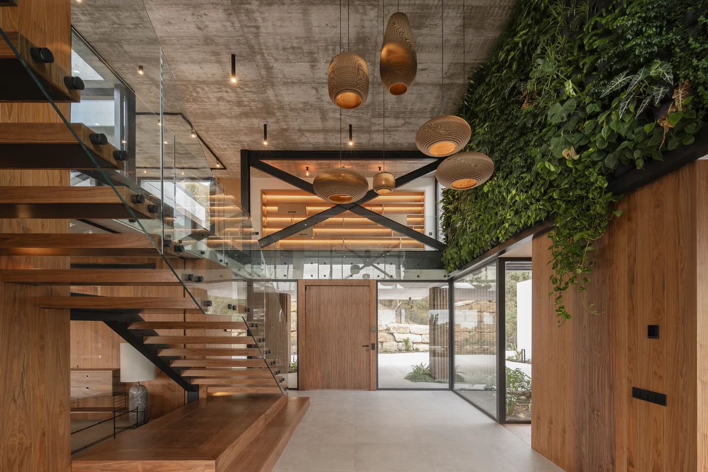 Escalera de madera y muro de hormigón visto en el interior de una villa de lujo