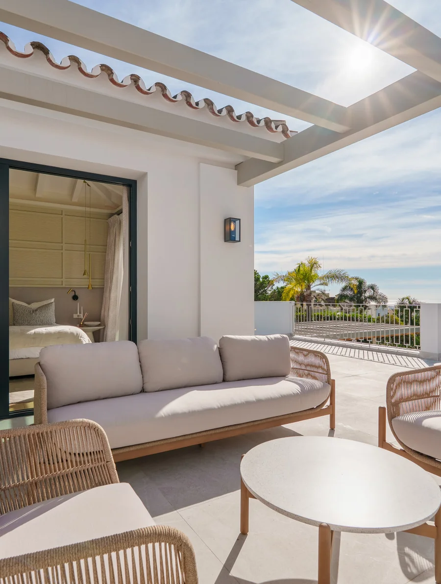 Terraza con pérgola y sofás exteriores tras la rehabilitación integral de Villa Agata