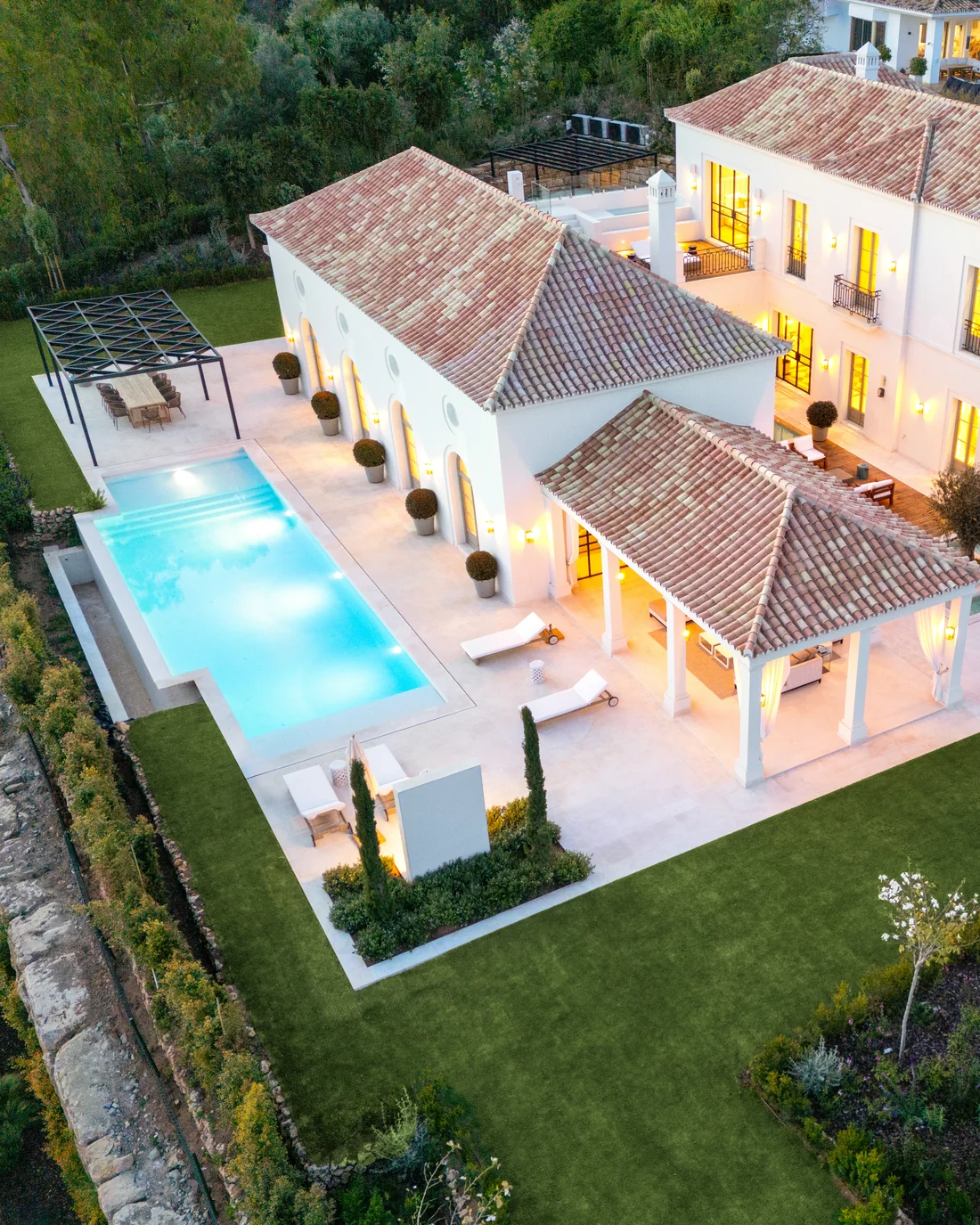 Aerial view of an Andalusian-style villa with pool and garden at dusk