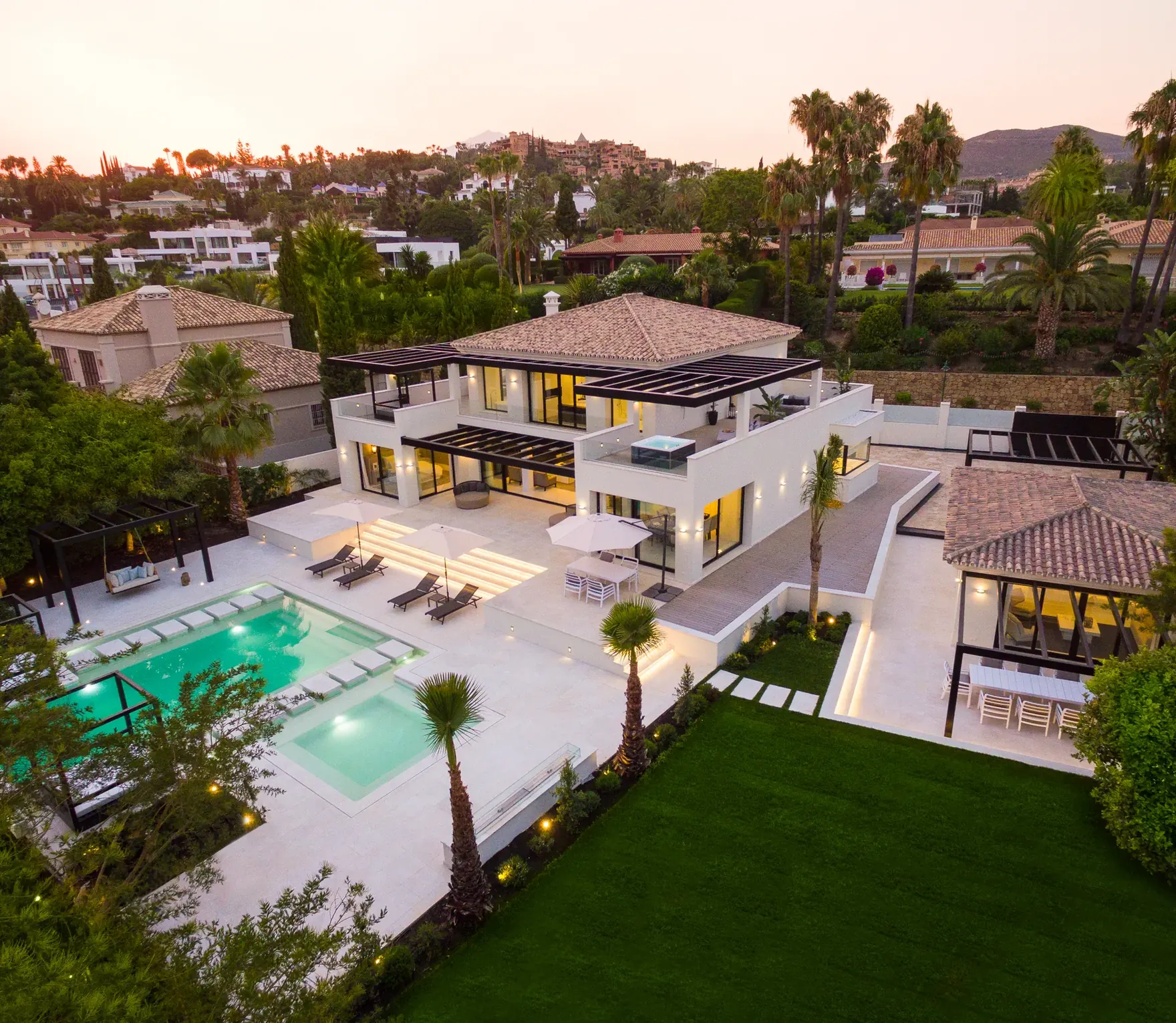 Villa de lujo con piscina y jardín rodeada de vegetación al atardecer