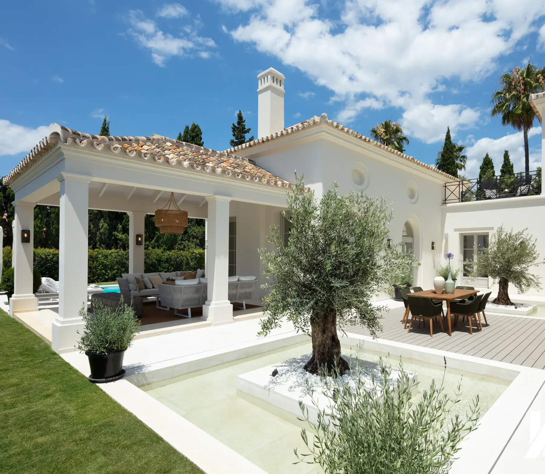 Villa de estilo andaluz con fachada blanca, porche y patio con olivo