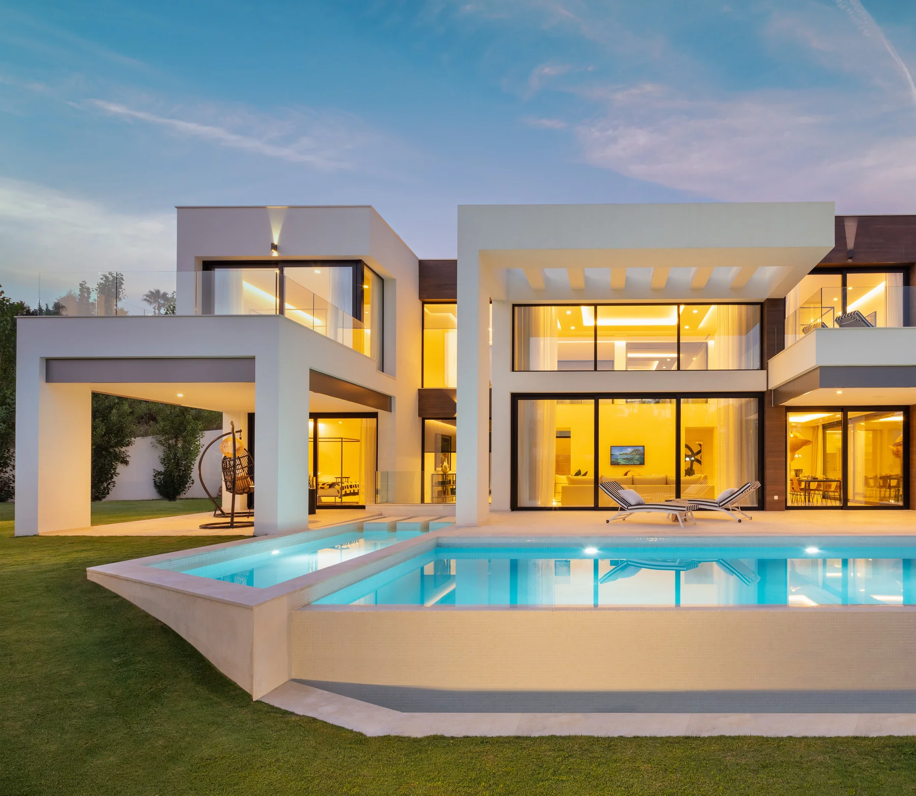 Contemporary villa illuminated at sunset with an infinity pool
